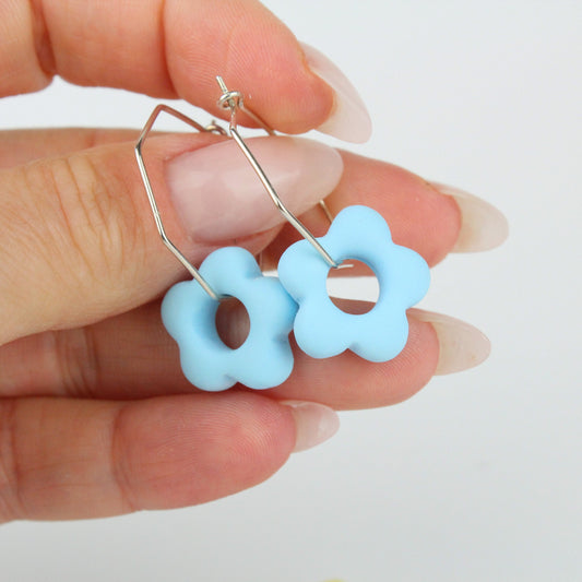 Sechseckige silberne Creole mit einem bunten Anhänger in Form einer Blume.