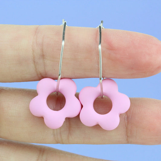 Sechseckige silberne Creole mit einem bunten Anhänger in Form einer Blume.