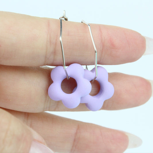 Sechseckige silberne Creole mit einem bunten Anhänger in Form einer Blume.