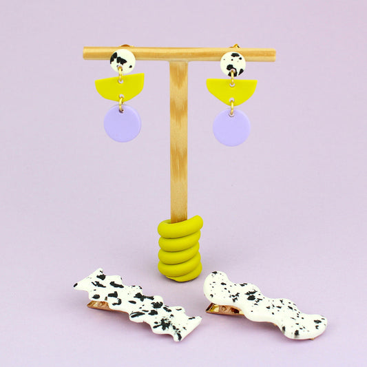 Ein handgemachtes Schmuck-Set bestehend aus einem Paar bunten Hängeohrringen und zwei passenden Haarspangen.