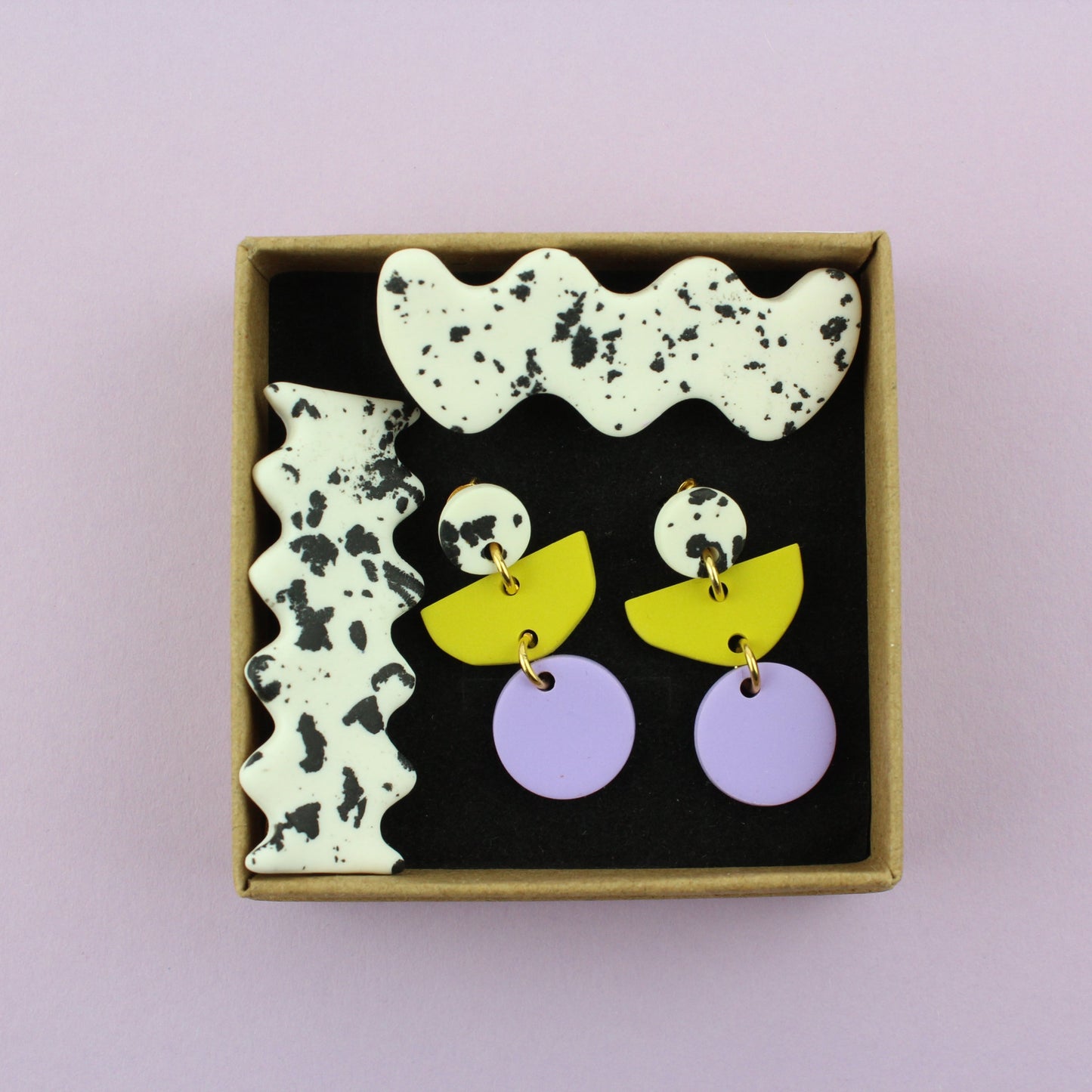 Ein handgemachtes Schmuck-Set bestehend aus einem Paar bunten Hängeohrringen und zwei passenden Haarspangen.