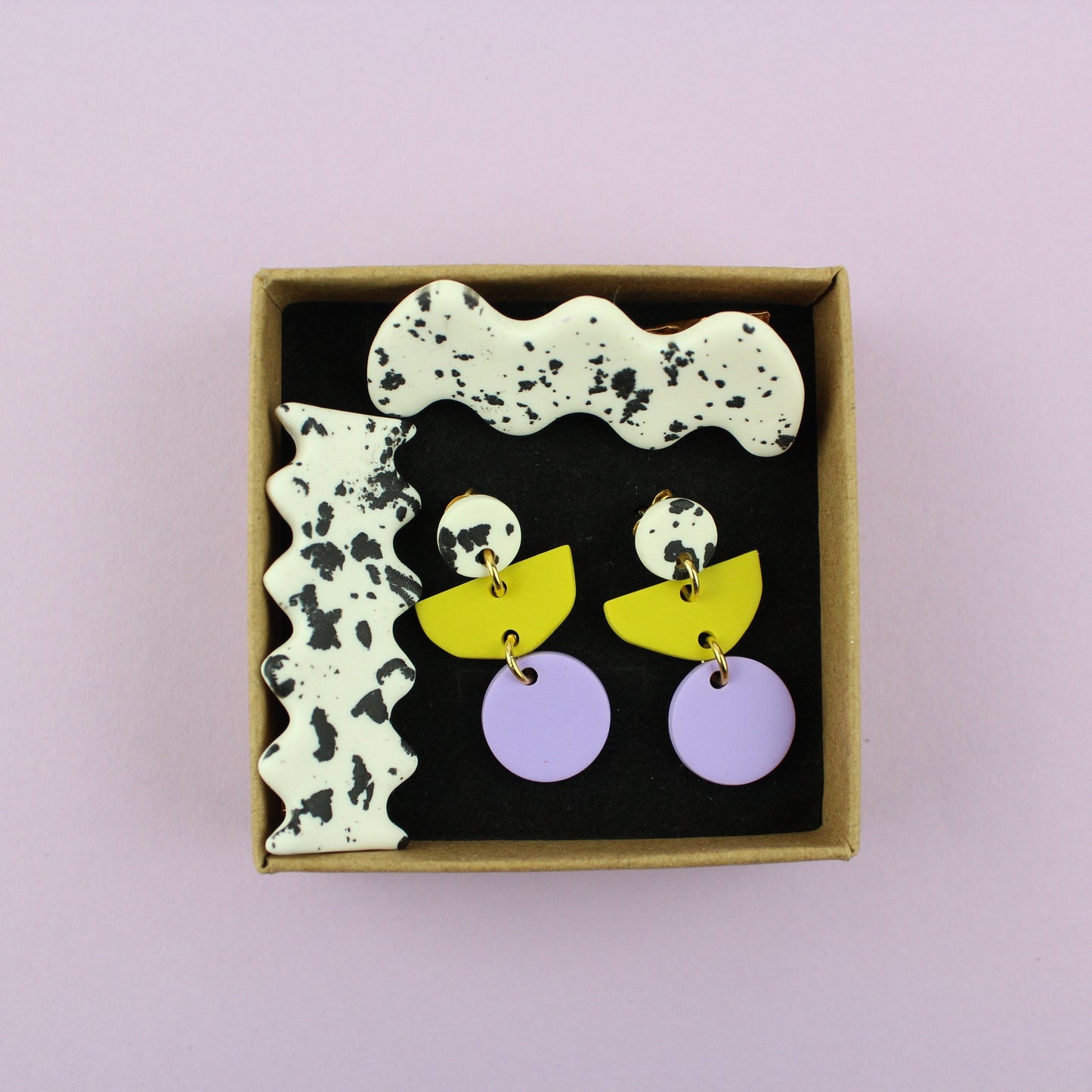 Ein handgemachtes Schmuck-Set bestehend aus einem Paar bunten Hängeohrringen und zwei passenden Haarspangen.
