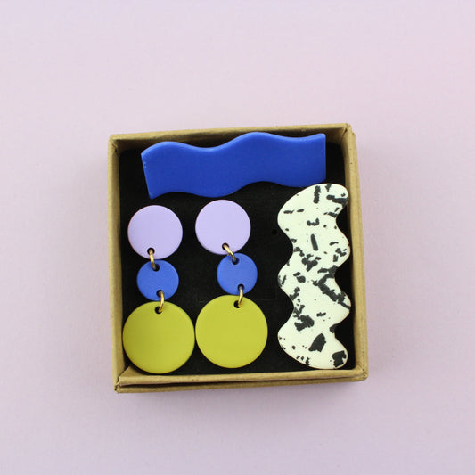 Ein handgemachtes Schmuck-Set bestehend aus einem Paar bunten Hängeohrringen und zwei passenden Haarspangen.