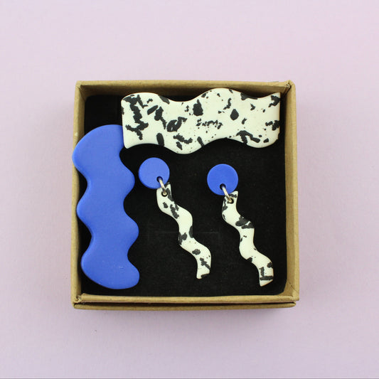 Ein handgemachtes Schmuck-Set bestehend aus einem Paar bunten Hängeohrringen und zwei passenden Haarspangen.