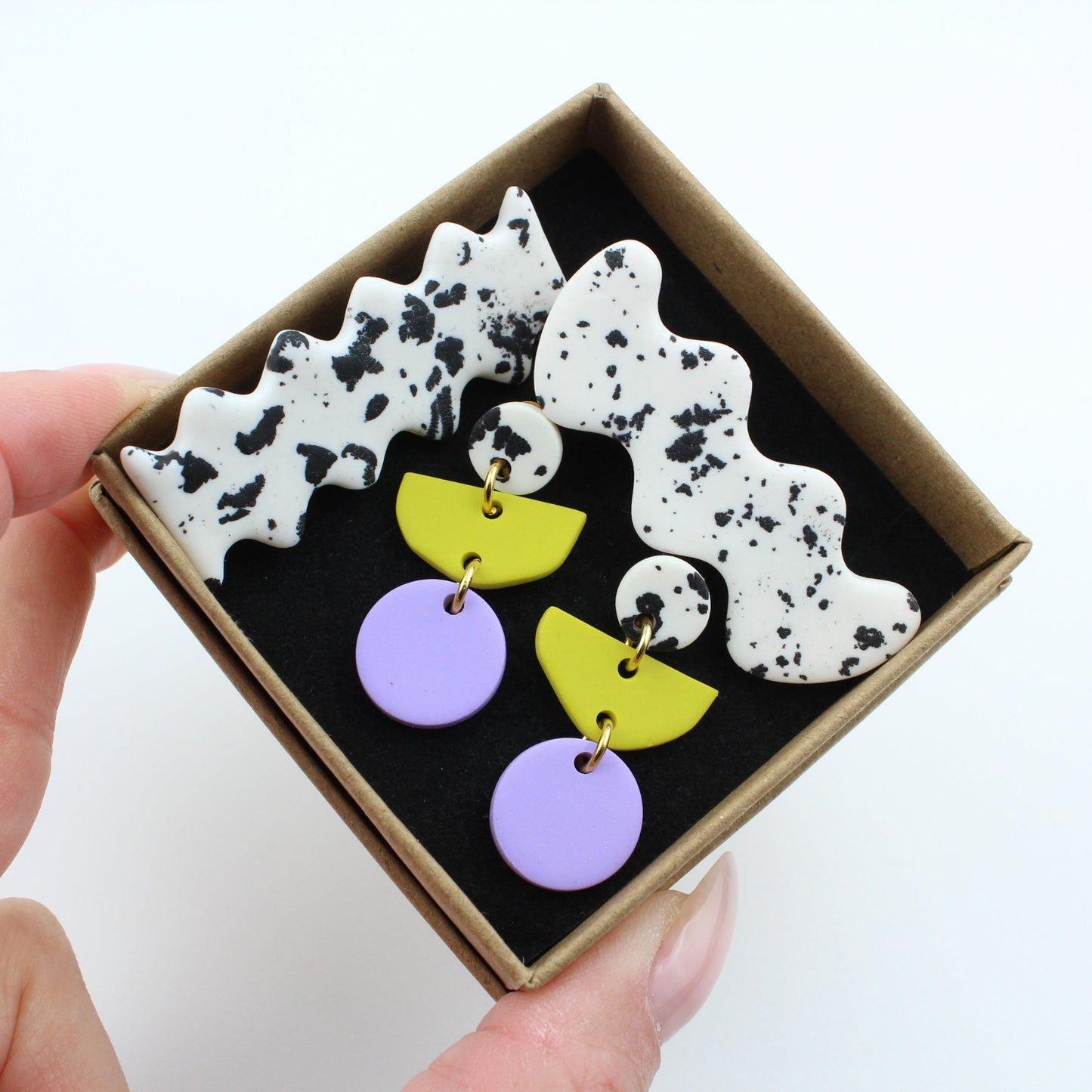 Ein handgemachtes Schmuck-Set bestehend aus einem Paar bunten Hängeohrringen und zwei passenden Haarspangen.
