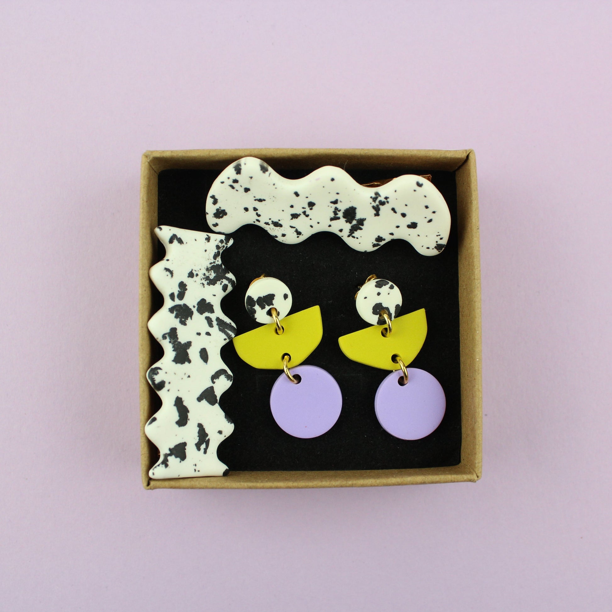 Ein handgemachtes Schmuck-Set bestehend aus einem Paar bunten Hängeohrringen und zwei passenden Haarspangen.