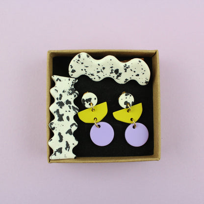 Ein handgemachtes Schmuck-Set bestehend aus einem Paar bunten Hängeohrringen und zwei passenden Haarspangen.
