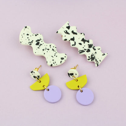 Ein handgemachtes Schmuck-Set bestehend aus einem Paar bunten Hängeohrringen und zwei passenden Haarspangen.