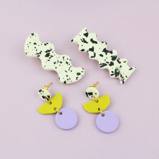 Ein handgemachtes Schmuck-Set bestehend aus einem Paar bunten Hängeohrringen und zwei passenden Haarspangen.
