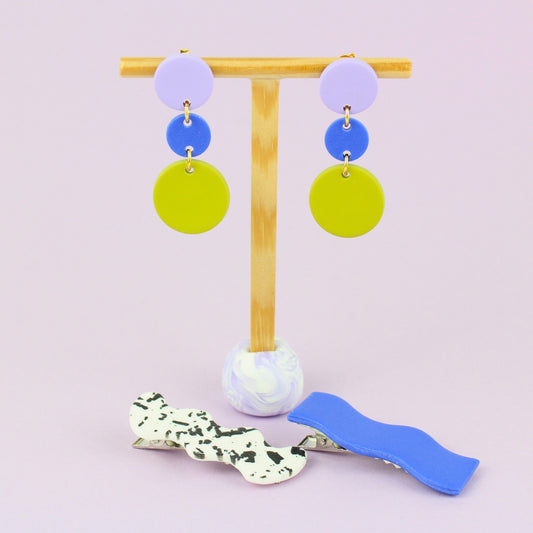 Ein handgemachtes Schmuck-Set bestehend aus einem Paar bunten Hängeohrringen und zwei passenden Haarspangen.