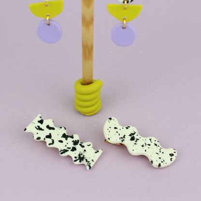 Ein handgemachtes Schmuck-Set bestehend aus einem Paar bunten Hängeohrringen und zwei passenden Haarspangen.